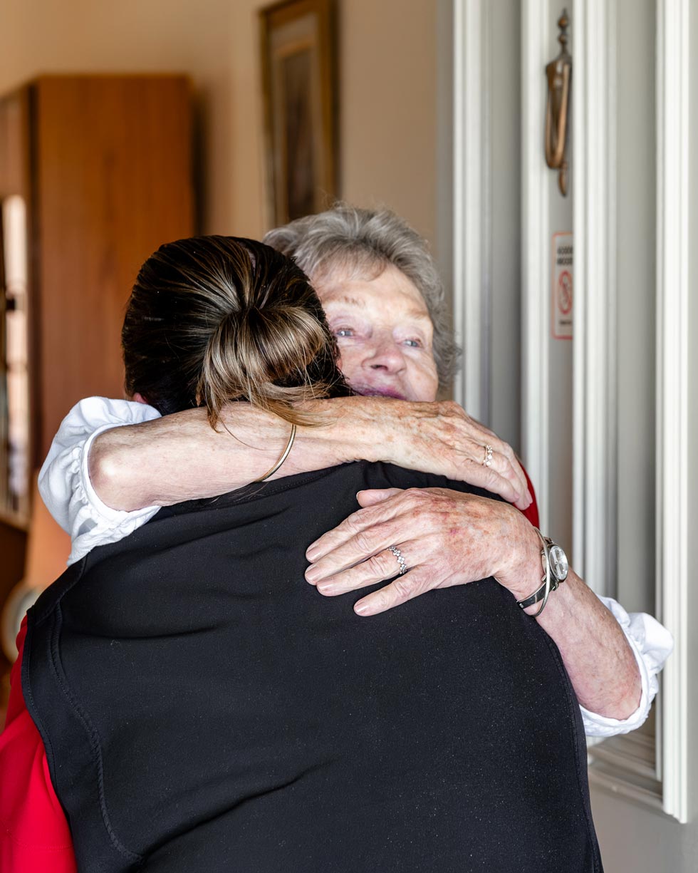 MHA Carer gives a warm hug to an elderly woman