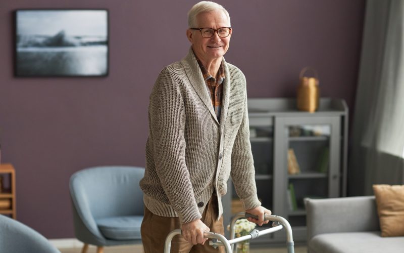 Elderly man walking with walker at home